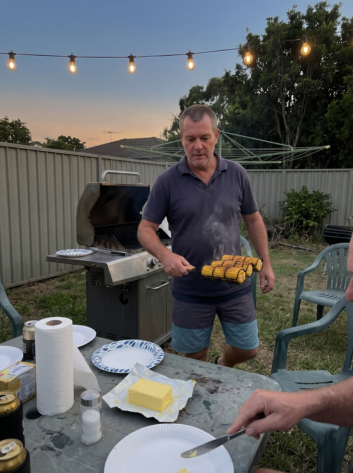 Carrying four charred cobs in the Cob Rack to the table at dusk